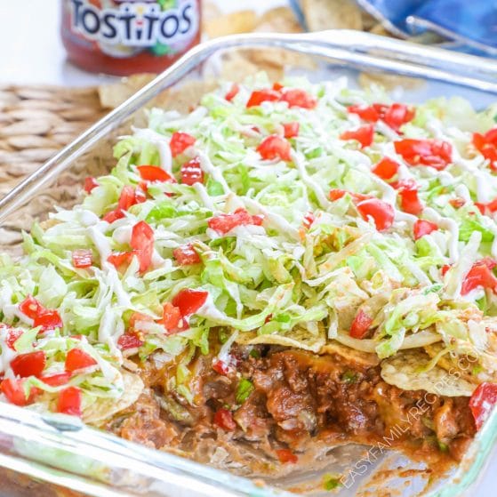 7 layer taco casserole in a dish showing layers of beans, meat, cheese, chips, lettuce and sour cream