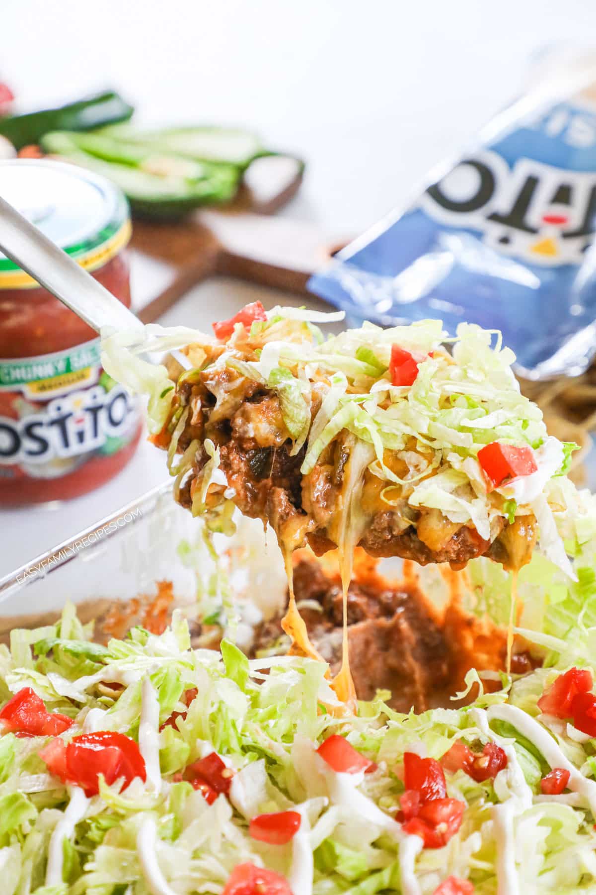 Spoon lifting ground beef taco casserole with cheese stringing.