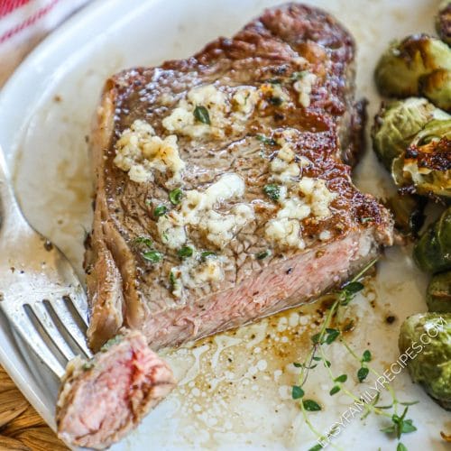 Medium Strip Steak smothered in garlic cut into on a plate