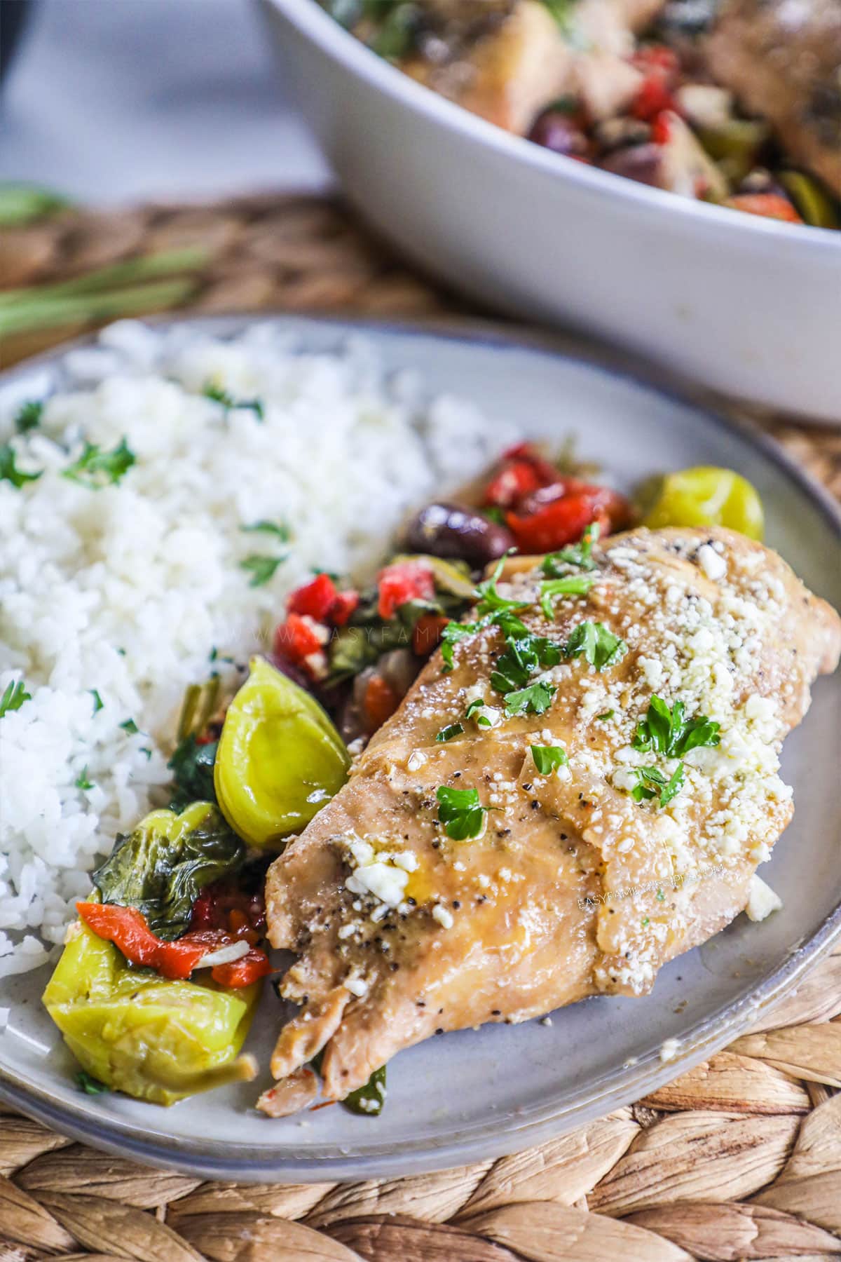 Greek chicken on a dinner plate with a side of rice