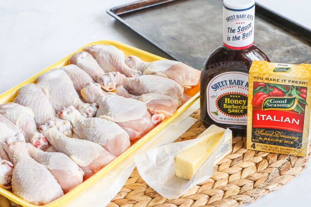 Ingredients for making baked chicken drumsticks including chicken legs, bbq sauce, butter, italian seasoning