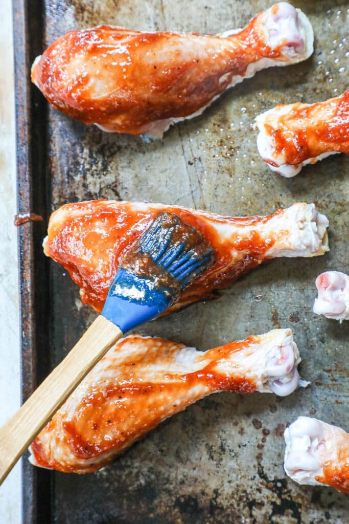 How to make Baked BBQ Chicken Drumsticks Step 3: Brush chicken legs with BBQ sauce all the way around.
