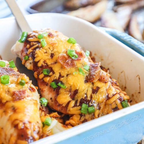 Chicken breast smothered in BBQ sauce, cheese, and bacon baked in a casserole dish and being lifted with a spatula