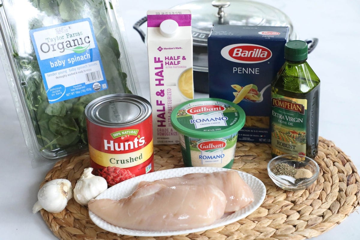 Ingredients for making Italian Chicken Pasta with chicken breast, crushed tomatoes, garlic, seasonings, parmesan, pasta, and half and half.