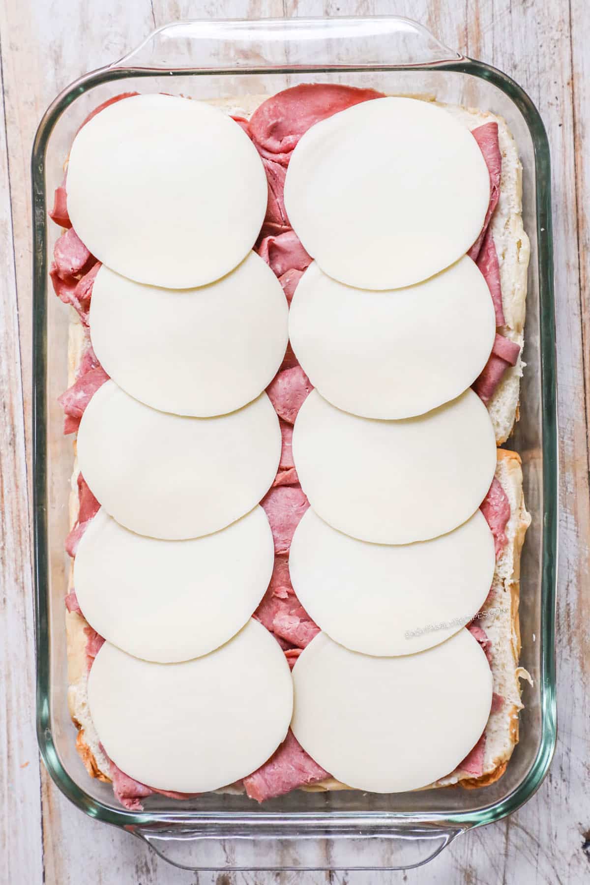 Process photos for how to make baked Roast Beef Sliders 2. Layer roast beef deli meat and cheese
