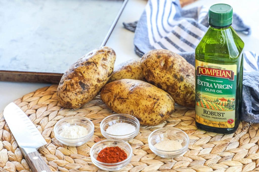 Ingredients for making baked potato wedges - potatoes, oil, salt, garlic powder, paprika, onion powder