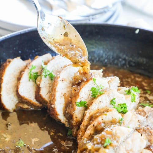 Spooning garlic sauce over pork tenderloin