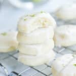 Bite sized key lime cookies stacked on a cooling rack.
