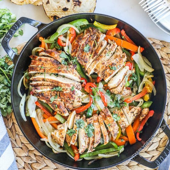 Chicken Fajitas prepared in a cast iron skillet Tex Mex style with onions, peppers, and lime.