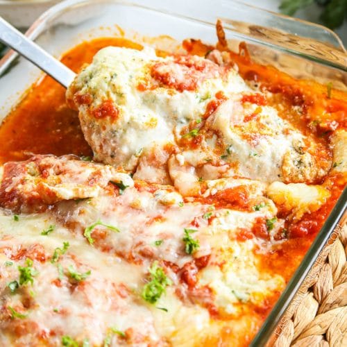 Lifting cheesy Lasagna Chicken breast from the dish to serve