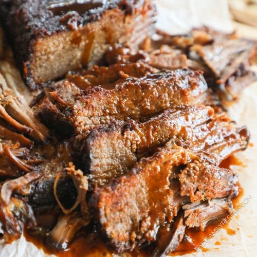 Brisket cooked in slow cooker taken out and sliced with BBQ sauce