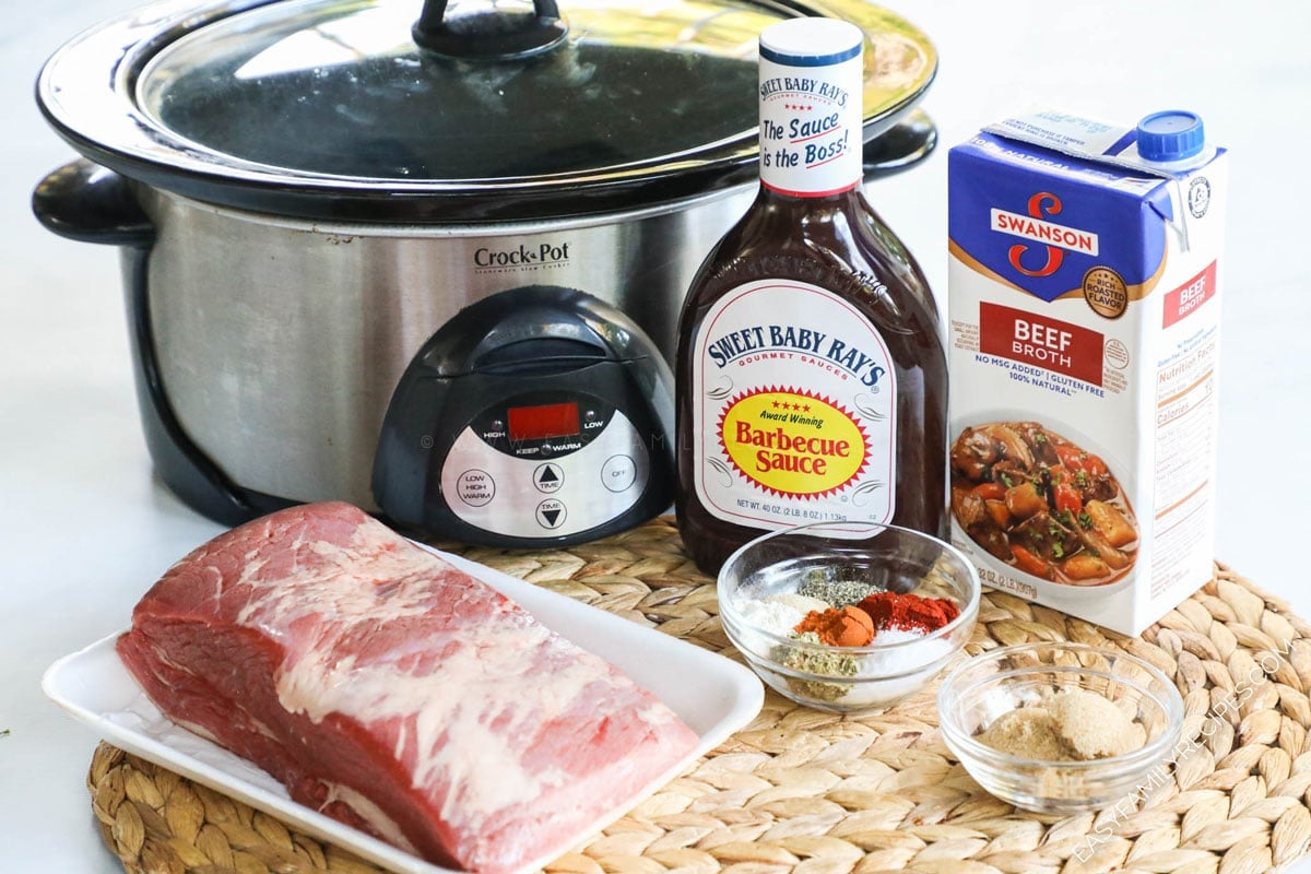 Ingredients for making Slow Cooker Brisket including beef brisket, BBQ sauce, broth, spices and crock pot