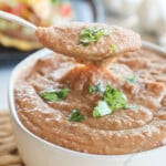 Scooping a spoonful of fresh homemade refried beans from serving bowl.