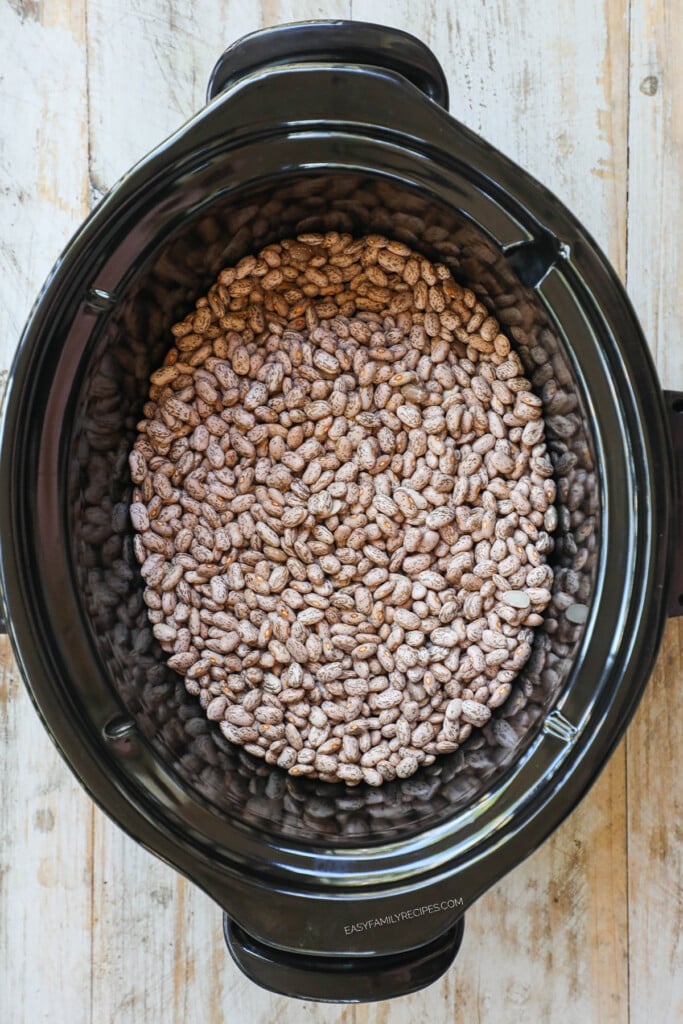 How to make slow cooker refried beans step 1: Pour pinto beans in the bottom of a crockpot.