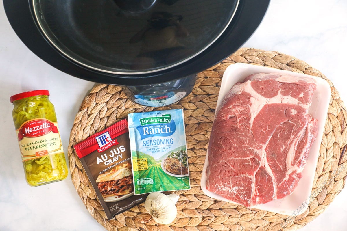 Ingredients for Crock Pot Mississippi Pot Roast including Chuck Roast, hidden valley ranch seasoning, au jus gravy packet, pepperoncini peppers.