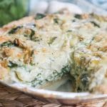 Slice cut out of Spinach Artichoke Quiche showing layers of spinach, artichokes and cheese in the egg custard.