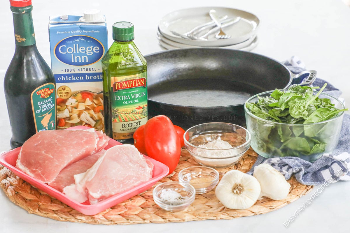 Ingredients for making Tuscan Pork Chops including boneless pork chops, tomatoes, balsamic vinegar, garlic, spinach, olive oil, and broth