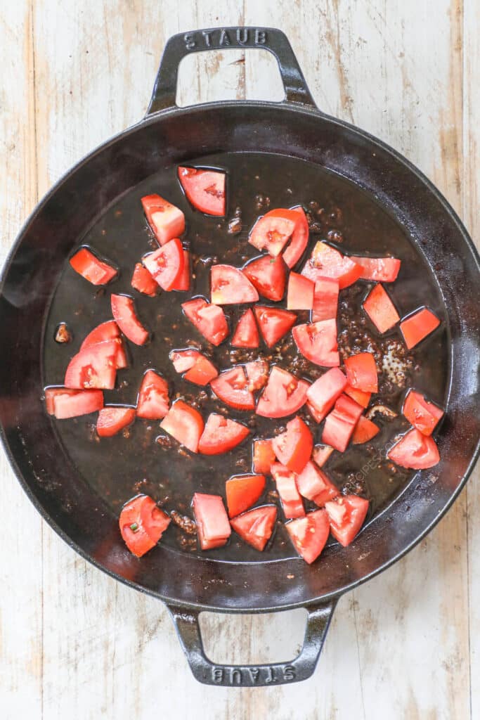 How to make Tuscan Pork Chops step 2: Chop tomatoes and balsamic with spices and cook in pan until they become jammy.