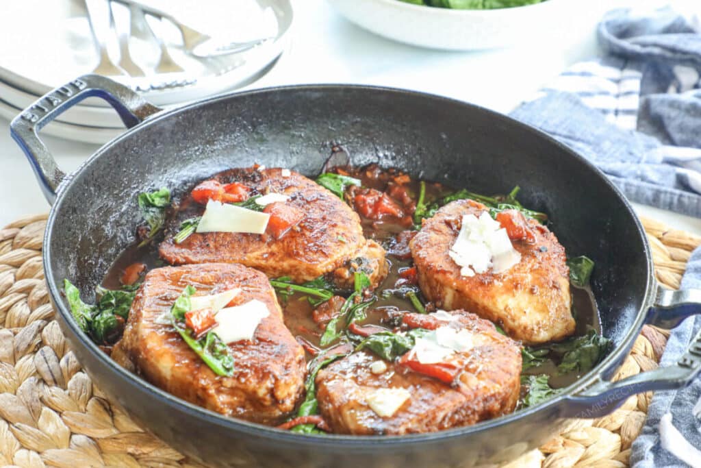 Four boneless pork chops prepared for dinner in a cast iron skillet.