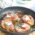 Four boneless pork chops prepared for dinner in a cast iron skillet.
