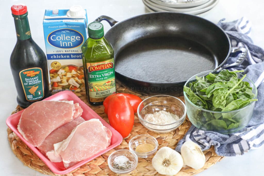 Ingredients for making Tuscan pork chops including boneless pork chops, flour, garlic, balsamic vinegar, chicken broth, tomatoes, and spinach.