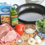 Ingredients for making Tuscan pork chops including boneless pork chops, flour, garlic, balsamic vinegar, chicken broth, tomatoes, and spinach.