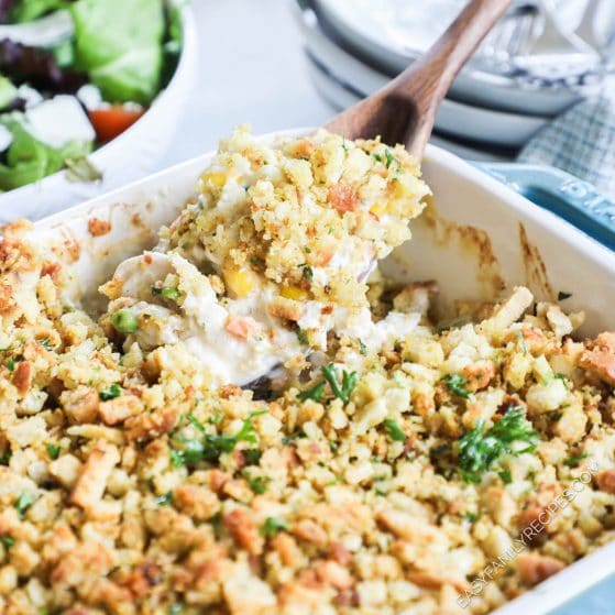 Chicken Stuffing Casserole recipe prepared in a casserole dish and being scooped with a wooden spoon
