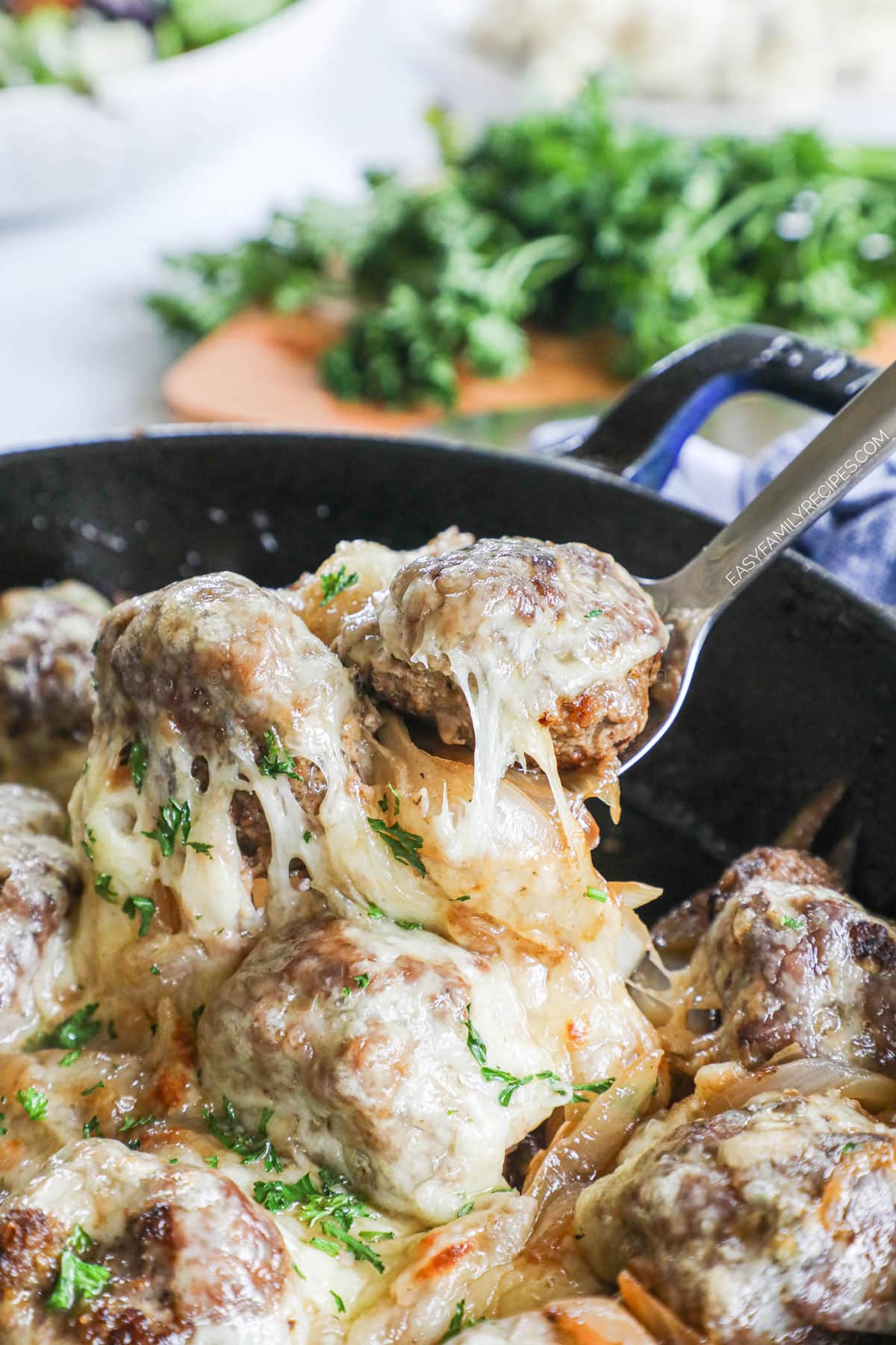 French onion meatballs being lifted from skillet to serve for dinner