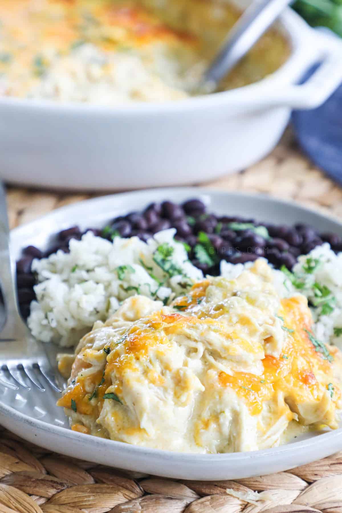 Green Chile Chicken on a plate with rice and black beans.