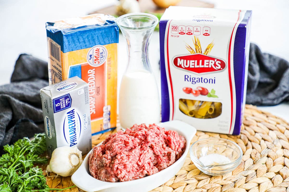 Ingredients to make cheeseburger pasta including ground beef, cream cheese, cheddar cheese, garlic, milk and pasta