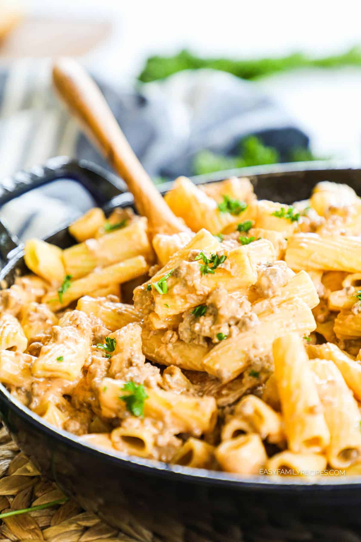Scooping cheeseburger pasta from skillet