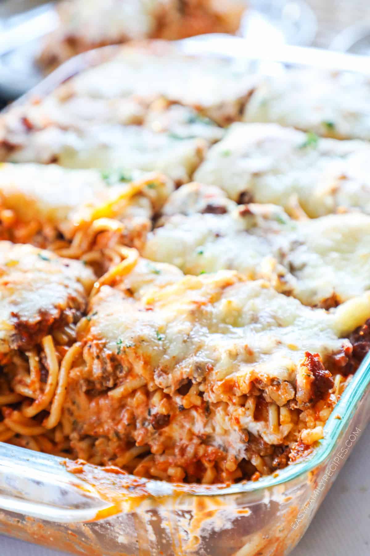 Cheesy Million Dollar Baked Spaghetti in a casserole dish sliced and ready to be served for an easy dinner