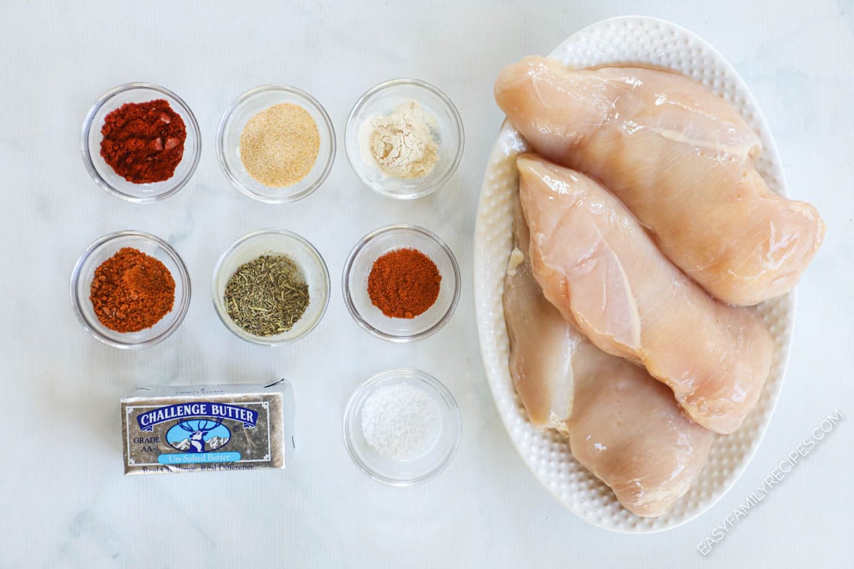 Ingredients for making blackened chicken including spices, butter, and chicken breast