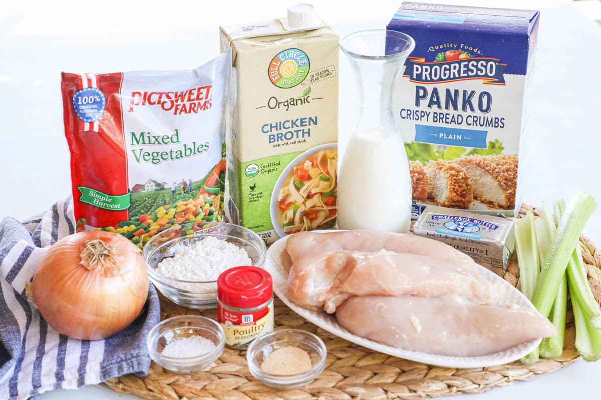 Ingredients for making crustless chicken pot pie including chicken breast, vegetables, seasoning, garlic, broth, bread crumbs