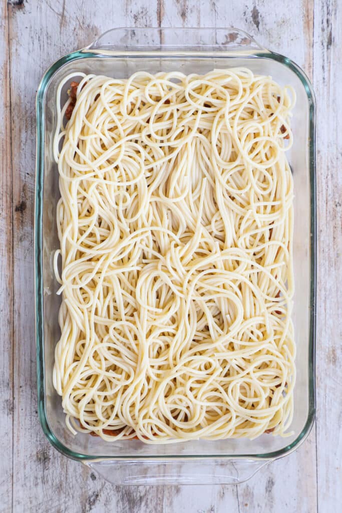 How to make million dollar spaghetti Step 1. Spread sauce in dish and layer spaghetti noodles on top.