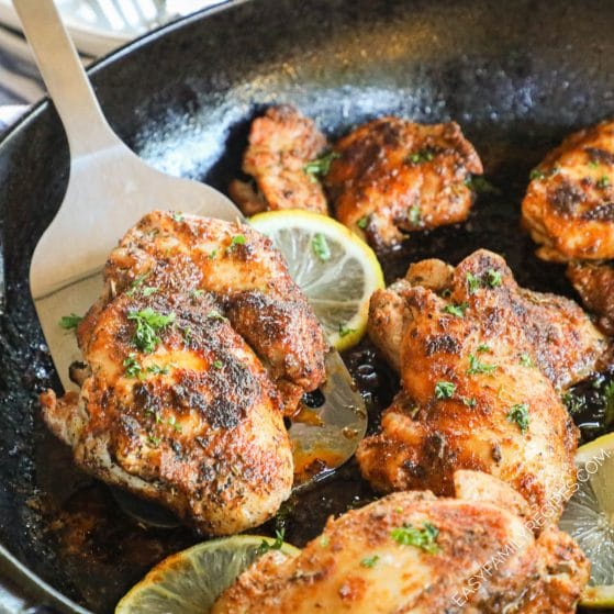 Seasoned blackened chicken thighs with lemon in a skillet