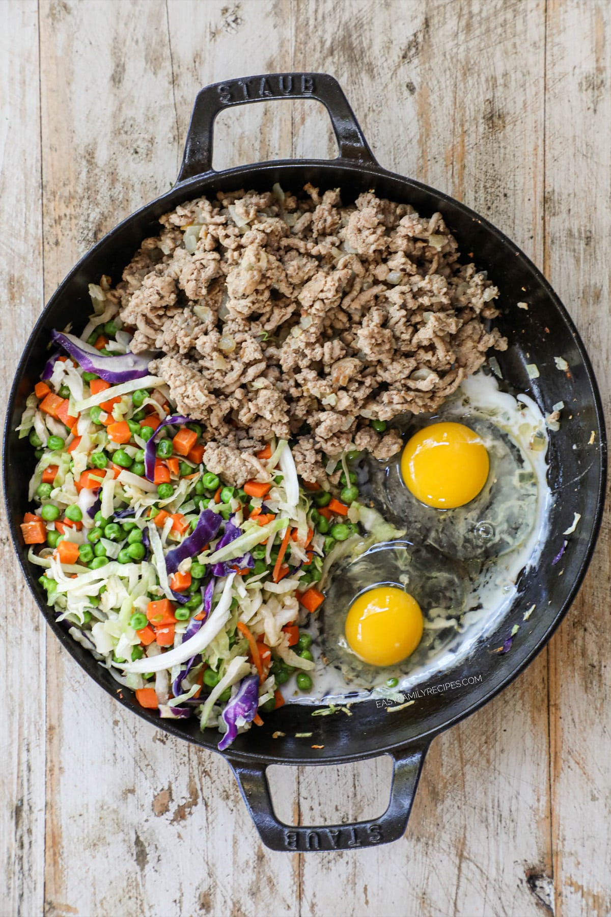 Push the veggies to the side, add the meat back into the skillet on the other side. Add the sesame oil to the bottom of the skillet and crack the eggs onto the leftover space.