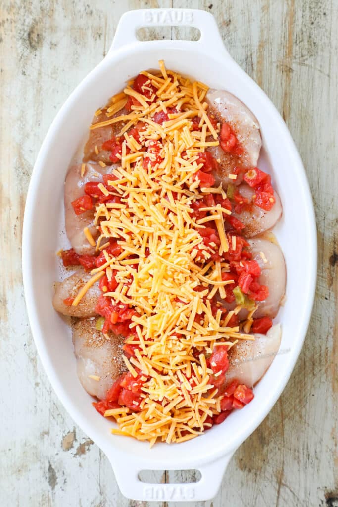 Overhead view showing how to make easy Rotel Chicken with the third step being to sprinkle cheese over the top of the Rotel tomatoes.