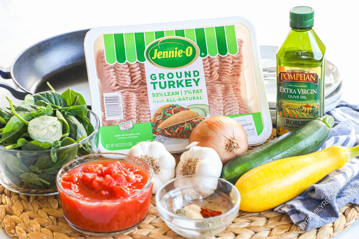 Ingredients to make Italian ground turkey skillet including lean turkey, canned tomatoes, spinach, squash, onion, and garlic.