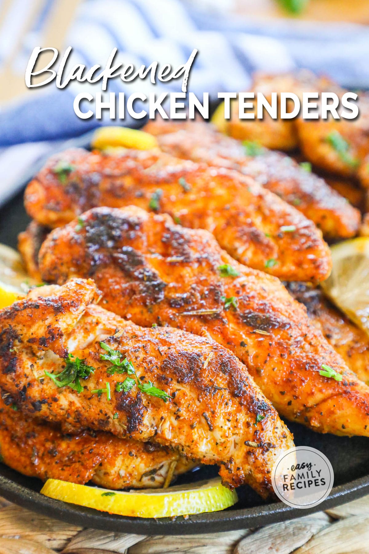 A pile of Blackened Cajun Chicken Tenders in a cast iron skillet with lemon wedge on the side.