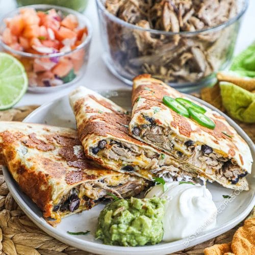 Crispy Carnitas quesadillas on plate served with guacamole, sour cream and jalapeno