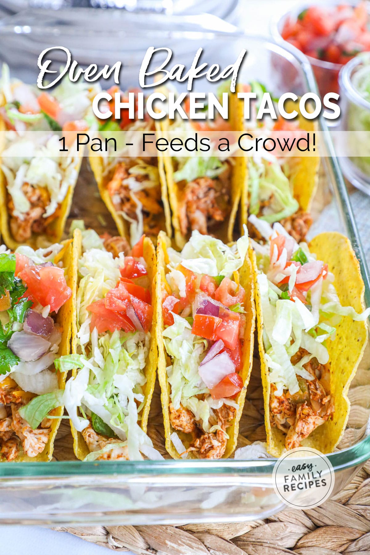 a pan of baked shredded chicken tacos with shredded lettuce and chopped tomatoes