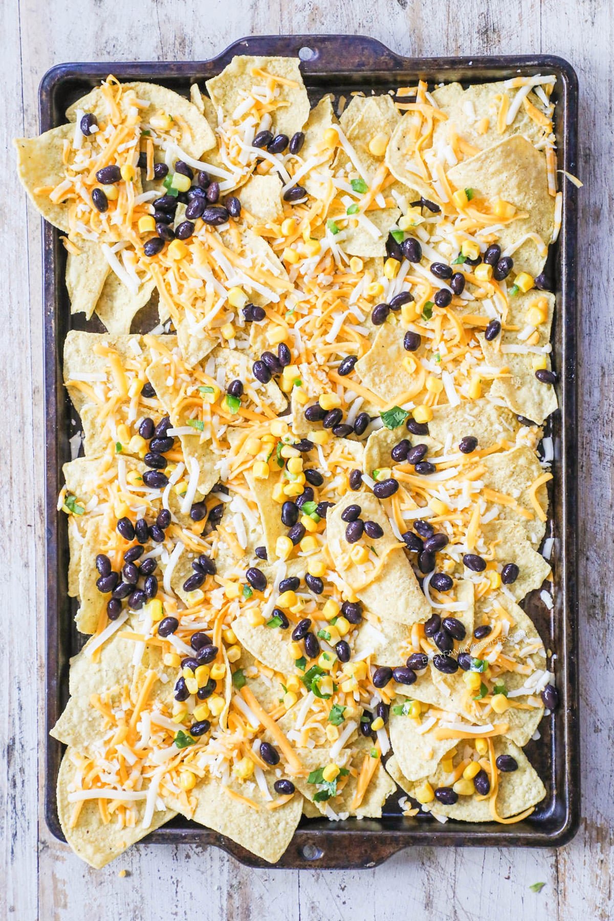 How to Make Carnitas Nachos: Step 2: Add corn and black beans to the top