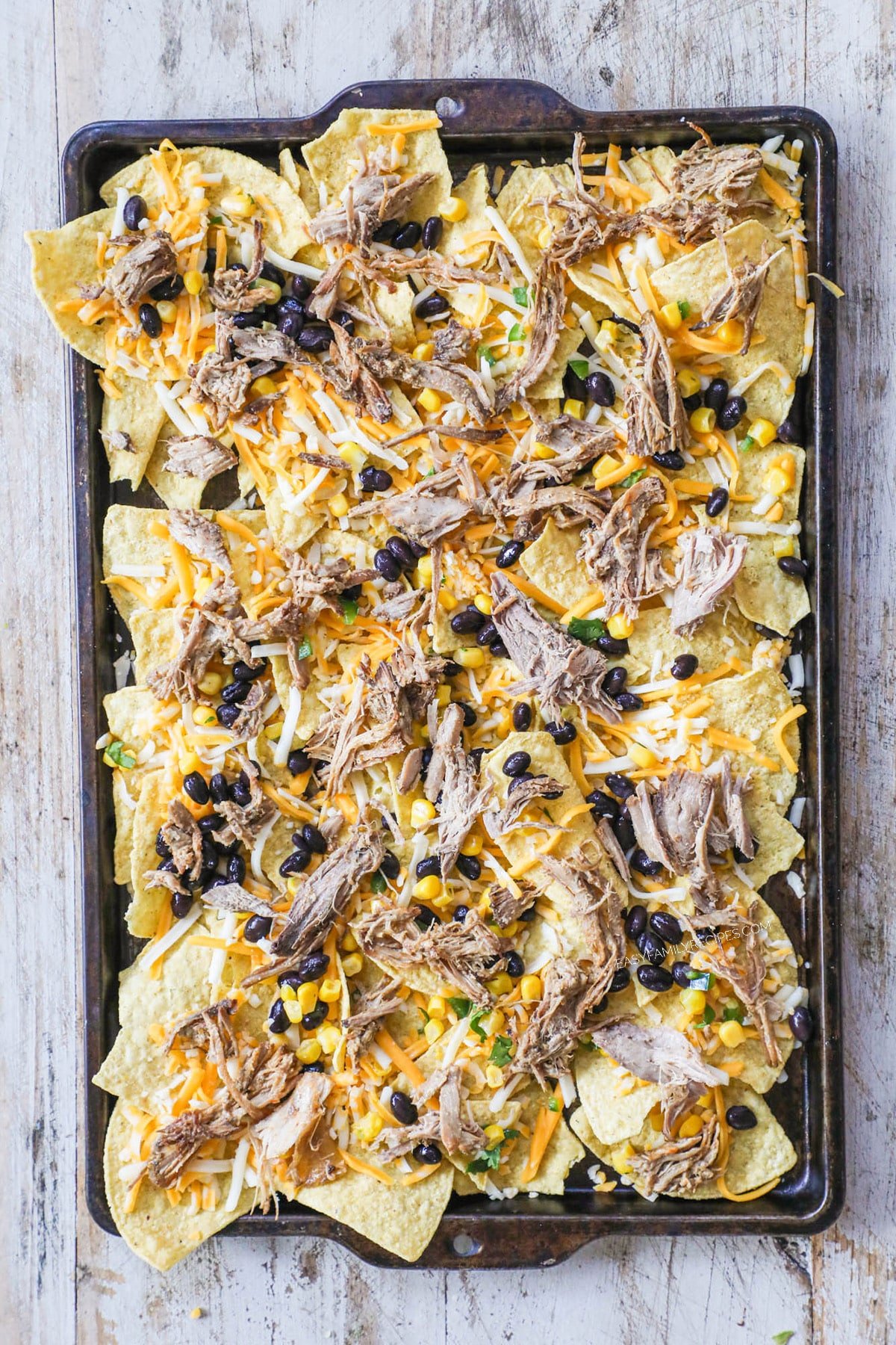 How to Make Carnitas Nachos: Step 3: Add carnitas and the remainder of cheese