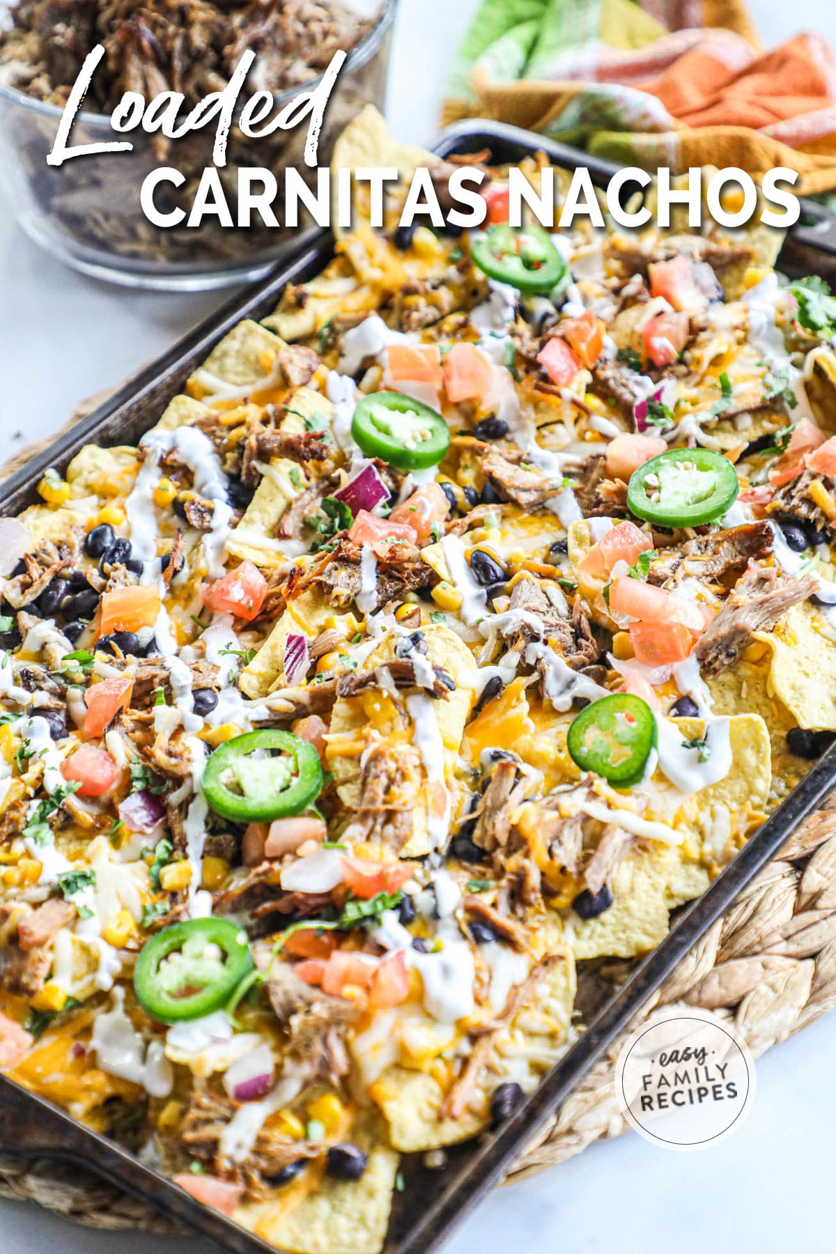 side view of pan of nachos with bowl of carnitas