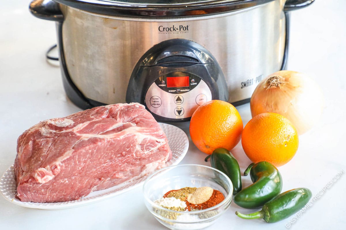 Ingredients to make Crock Pot pork carnitas including pork shoulder, oranges, jalapenos, and seasonings