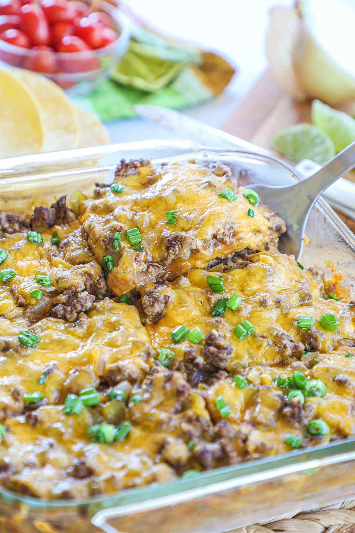 Image of baked enchilada casserole cut into 6 portions with serving spoon removing one portion.