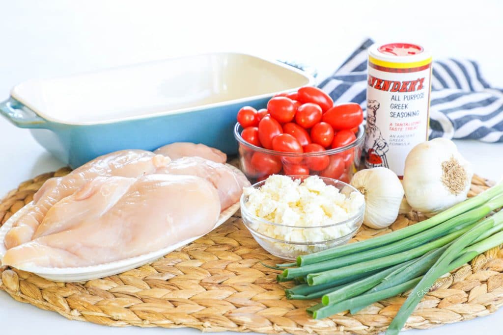 Ingredients to make feta tomato chicken bake cherry tomatoes, green onion, garlic, greek seasoning, and chicken breast.