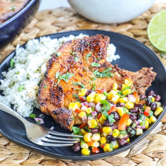 Pan seared pork chop served over rice and topped with corn salsa