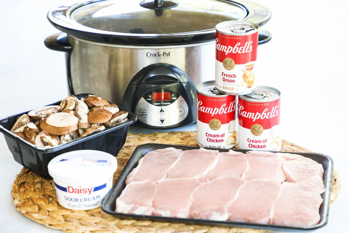 Ingredients for making crockpot smothered pork chops including boneless pork chops, cream of chicken soup, french onion soup and mushrooms.